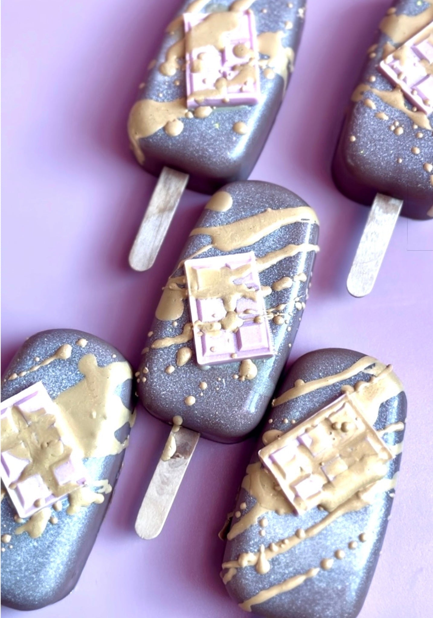 Birthday cake–inspired luxury popsicle soaps featuring shimmering brown bases, golden drizzle, and confection-style topping by Decadent Body Bar.